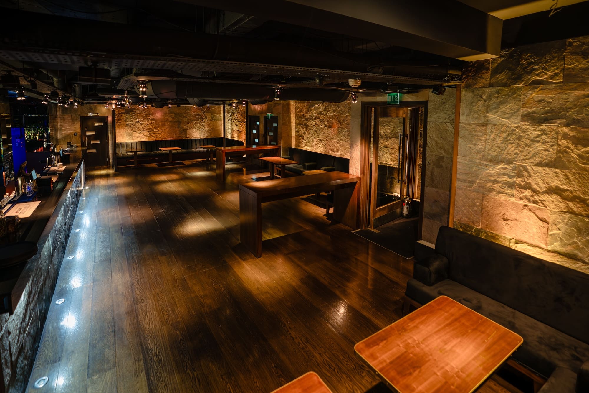 Intimate leather booths and rustic wooden tables in the basement venue of Purl Barbican, set up for exclusive hire