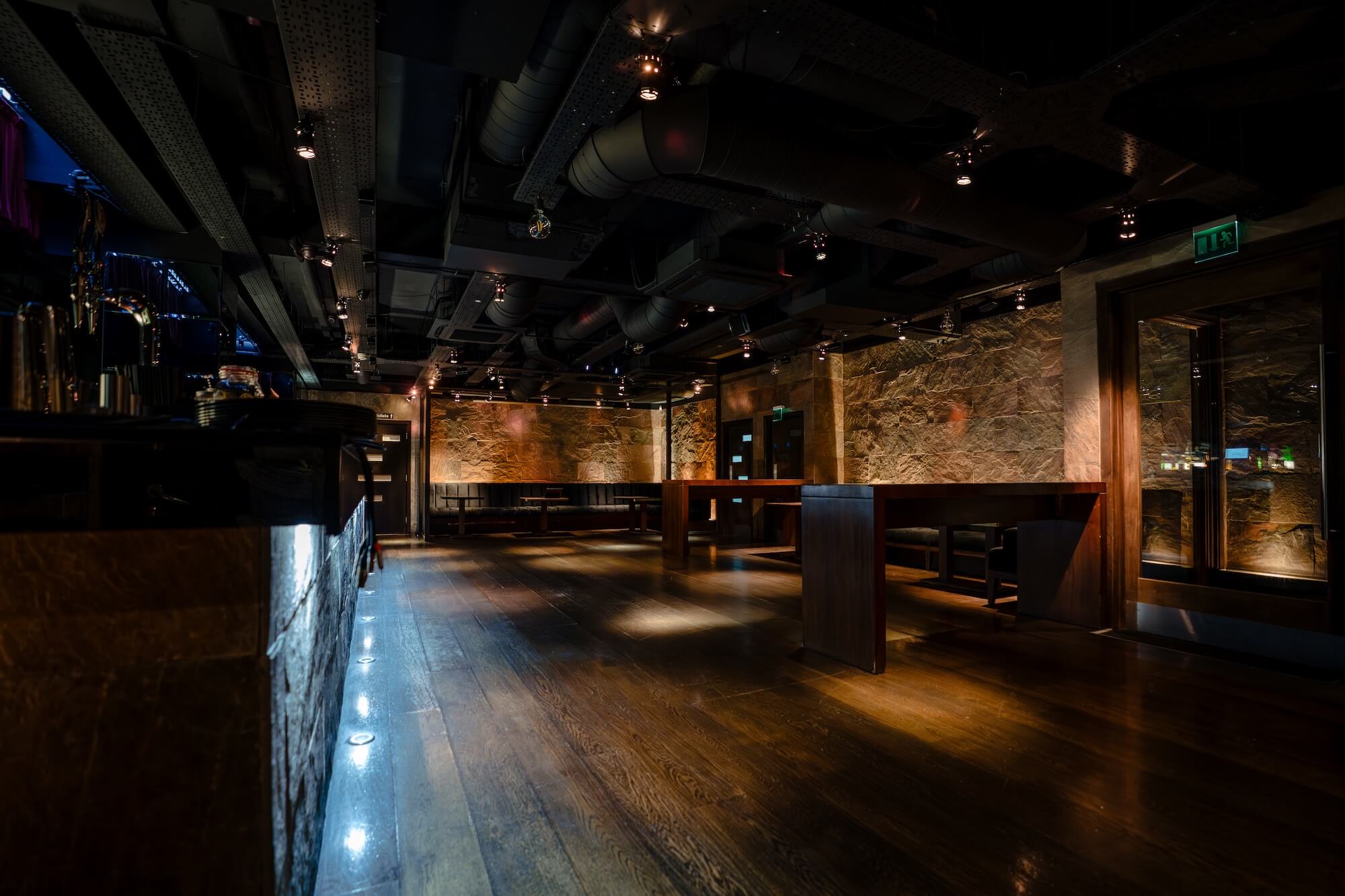 Interior detail of Purl Barbican event room showcasing exposed stone walls, brass accents, and warm, atmospheric lighting